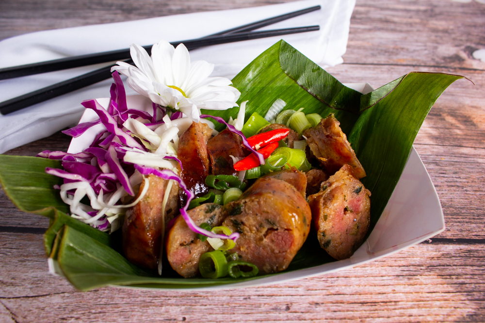 20220121_LanXang_Lao_Street_Food_(US-19)_03_Sai_Aor Example of Food Photography for DoorDash, Uber Eats, Grub Hub, and any food delivery service app. Food Photo is of a vietmanese dish garnished with flowers and other greenery.