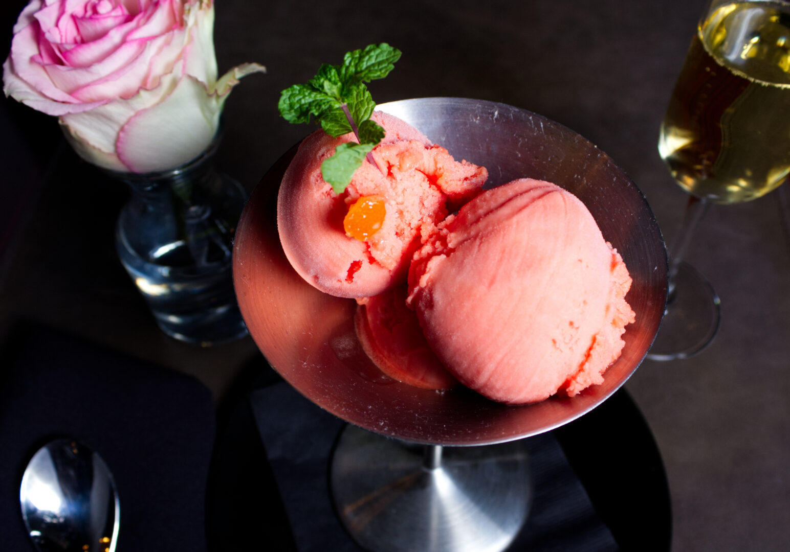 Image_10 Example of Food Photography for DoorDash, Uber Eats, Grub Hub, and any food delivery service app. Food Photo is of a pink sorbet served in a silver dish. Scene is ecorated with a pink rose to match the ice cream. Background is a dark surface.