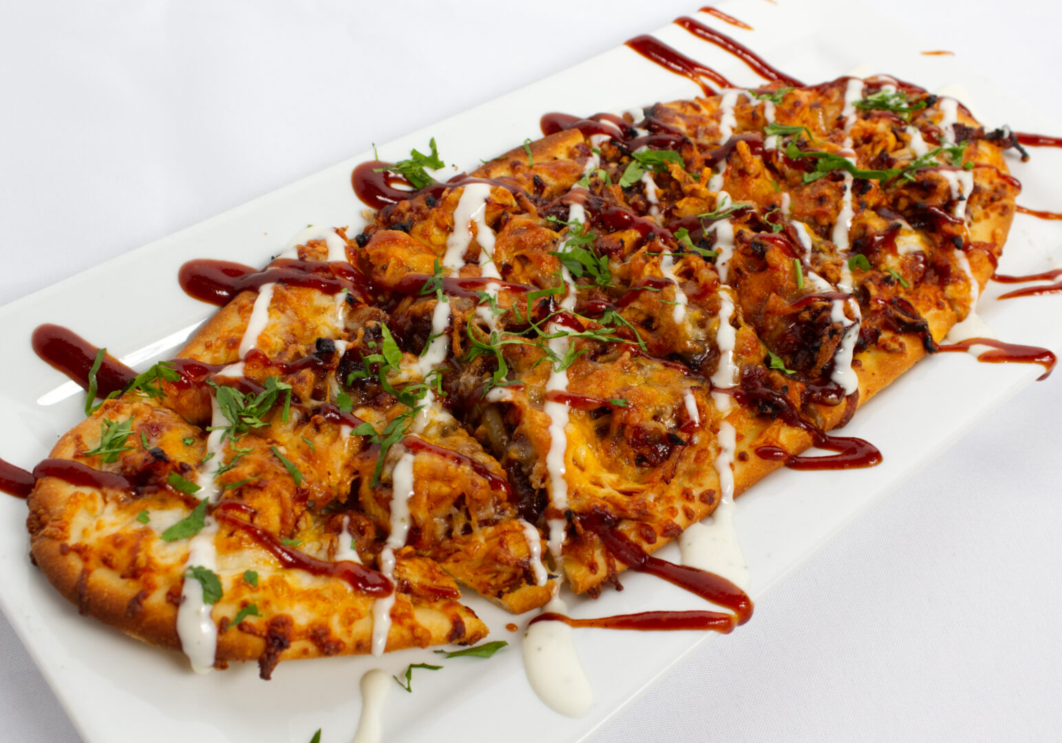 Image_02 Example of Food Photography for DoorDash, Uber Eats, Grub Hub, and any food delivery service app. Food Photo is a BBQ Chicken flatbread positioned diagnally on a elonged white palte. The background is white to showacase food.