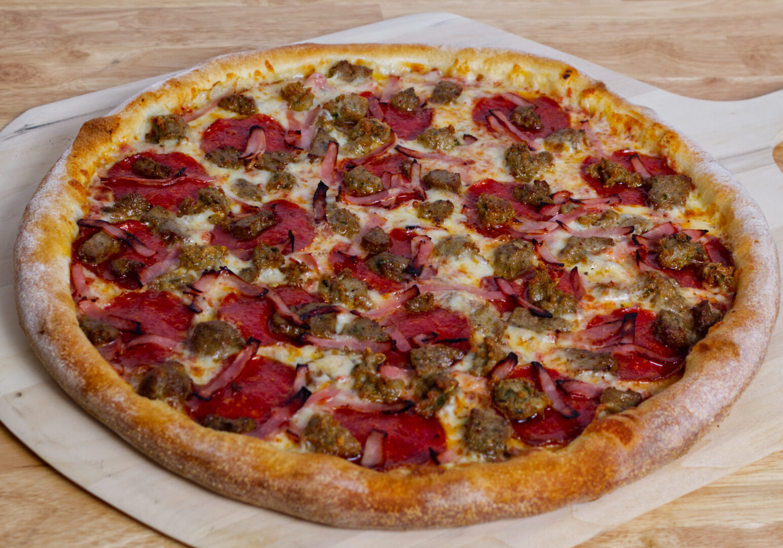 Image_03 Example of Food Photography for DoorDash, Uber Eats, Grub Hub, and any food delivery service app. Food Photo is of a pepperoni and sausage pizza on a wooden pizza paddle. The background is a chopping block style wood table.